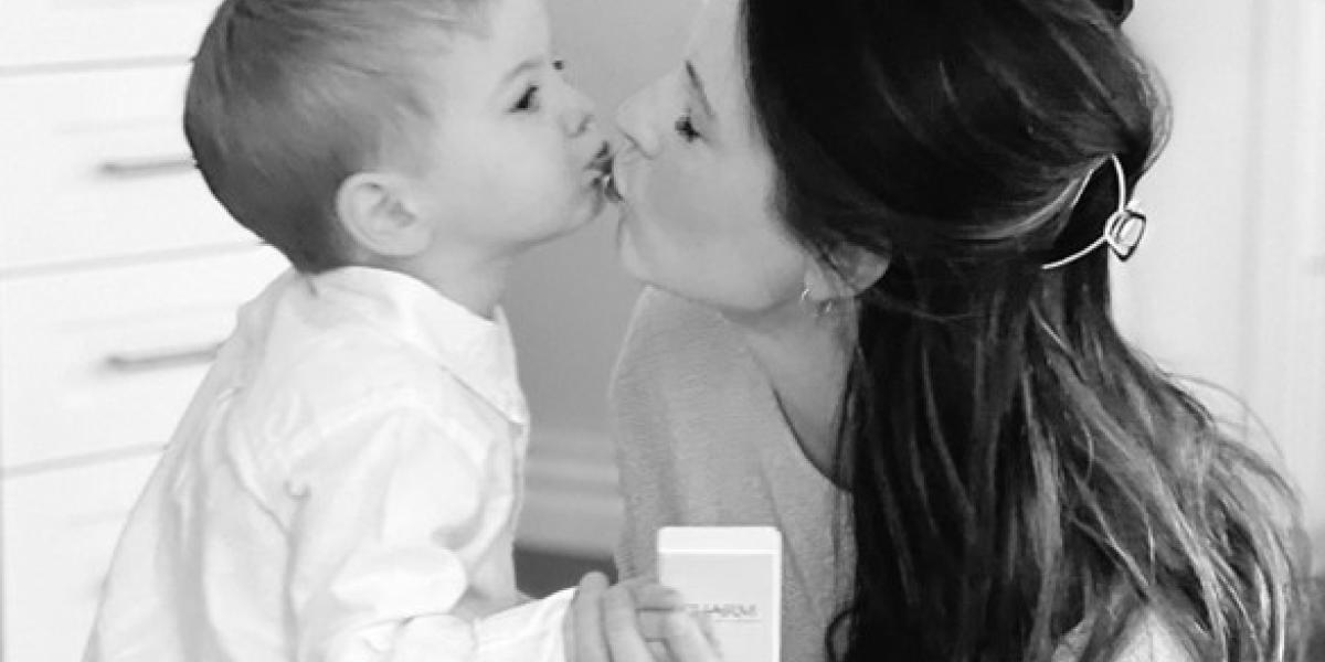 Photo of a mother and her baby sharing a loving kiss while he hands her a Charm Diamonds gift box 