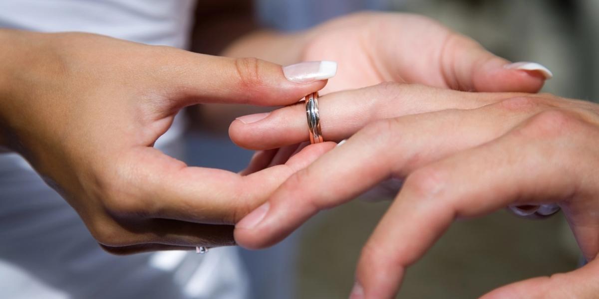 An engagement ring being placed on a man’s finger.