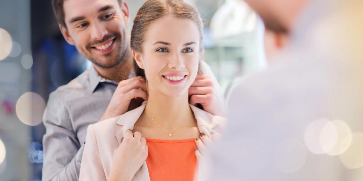 Couple trying on golden pendant at a jewellery store