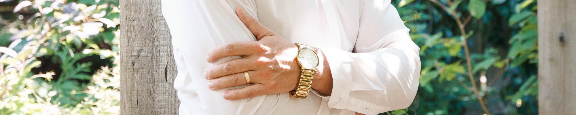 Man folded arms wearing gold watch