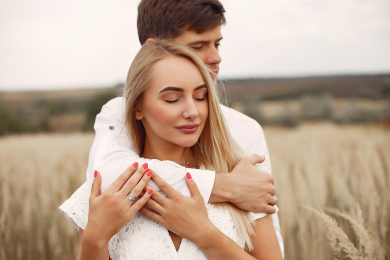 Couple embracing in front of field