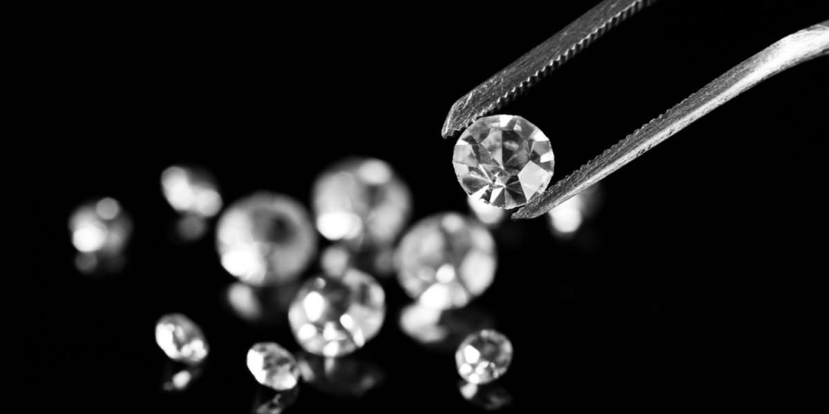 Beautiful shining diamond being held by tweezers on a black background